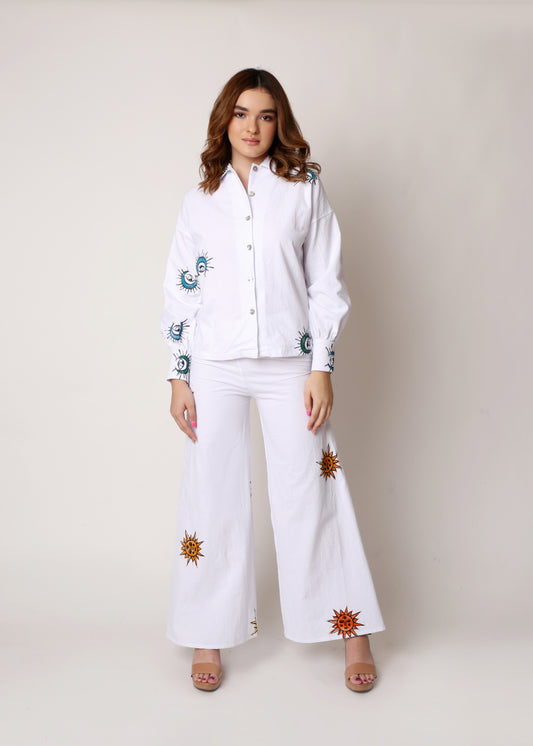Camisa holgada blanca con estampado de lunas azules y pantalón blanco con estampado de soles.